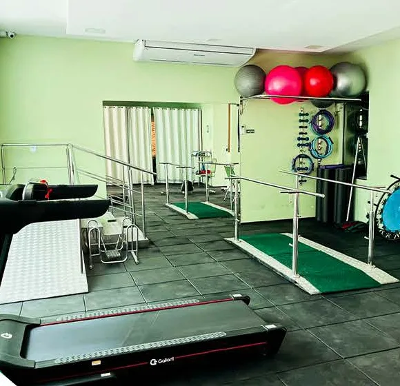Sala de fisioterapia com esteira, barras paralelas e bolas